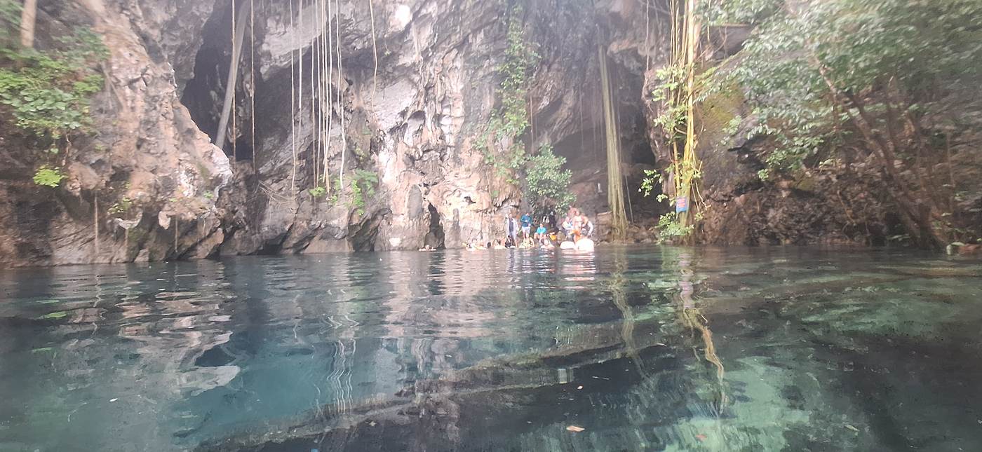 Águas cristalinas da Lagoa do Japonês com paredões de pedra e raízes ao fundo